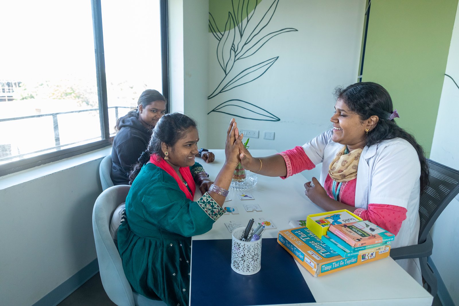 Therapist engaging in speech therapy with a young woman at a hearing implant clinic.